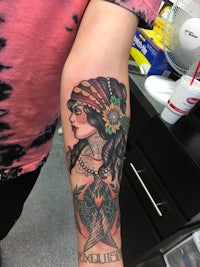 a tattoo of a woman with a bird on her arm