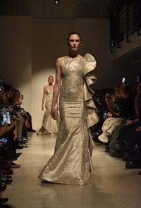 a model walks down the runway in a silver gown