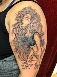 a tattoo of a woman with flowers on her arm
