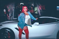 a woman in red thigh high boots standing next to a white sports car