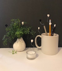 a mug with pencils and a plant next to it