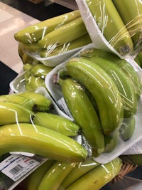 a bunch of green bananas in a basket