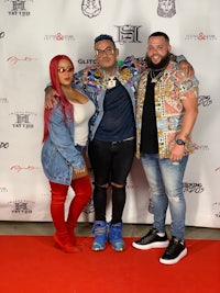 three people posing for a photo on a red carpet