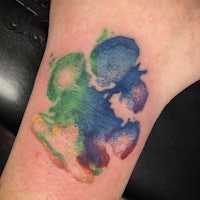 a colorful paw print tattoo on a woman's wrist