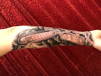 a tattoo of a knife on a person's forearm