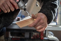 a person using a drill to make a piece of wood