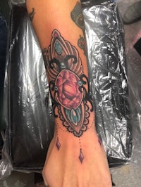 a woman's wrist with a pink and blue tattoo