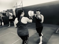 two women practicing boxing in a gym