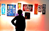 a person standing in front of a group of paintings