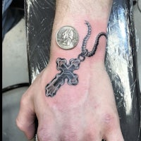 a black and grey cross tattoo on a man's wrist