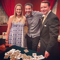 three people posing for a picture next to a table of cards