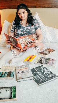 a woman sitting on a bed reading books