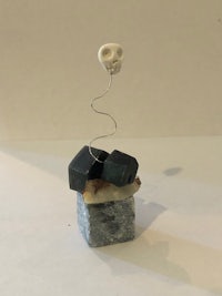 a sculpture with a skull on top of a piece of rock