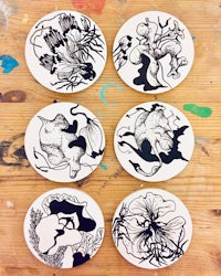four coasters with black and white drawings on them