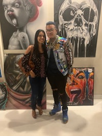 a man and woman posing for a photo in front of art
