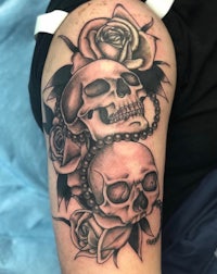 a tattoo of skulls and roses on a woman's arm