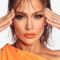 jennifer lopez in an orange dress with her hands on her face