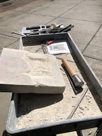 a wheelbarrow with tools on it sitting on a sidewalk