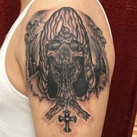 a tattoo of a skeleton with a cross on his shoulder