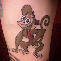 a cartoon monkey tattoo on a woman's thigh