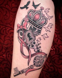 a tattoo with a crown and key on the leg