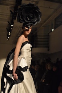 a woman wearing a black and white dress on the runway