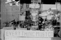 a black and white photo of a store window with a sign that says everything must go