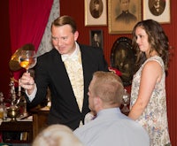 a man is holding a glass of wine in front of a woman