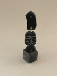 a black stone sculpture of a fish sitting on top of a block