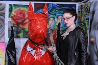 a woman wearing glasses next to a red dog statue