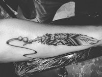 a black and white image of a feather tattoo
