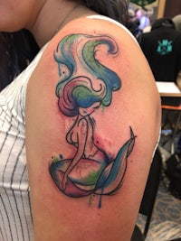 a tattoo of a mermaid with colorful hair