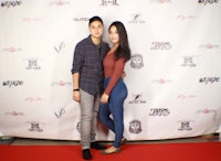 a man and woman posing on a red carpet
