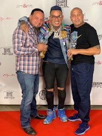 three men posing for a photo on a red carpet