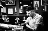 a man getting tattooed in a black and white photo