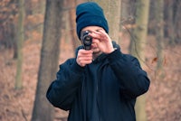 a man holding a camera in the woods