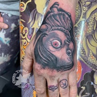 a hand with a tattoo of a doll on it