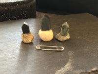 three small stones and a metal pin on a rock