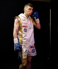 a man in a boxing uniform standing in a dark room