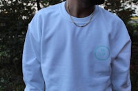 a man wearing a white sweatshirt with a green circle on it
