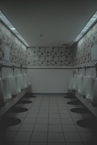 a row of urinals in a dark bathroom