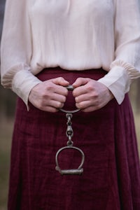 a woman holding a handcuff in a field