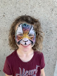 a little girl with a face painted like a lion