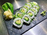 a plate of sushi with avocado, cucumber and sesame seeds