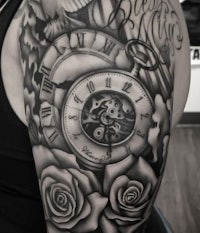 a tattoo of a clock and roses on a man's sleeve