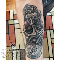a tattoo of an anchor and compass on a man's forearm