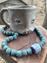 a blue beaded necklace with a mug on it