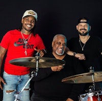 three men with drums posing for a photo