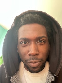 a black man in a hoodie looking at the camera