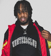 a man with dreadlocks wearing a jacket and hoodie